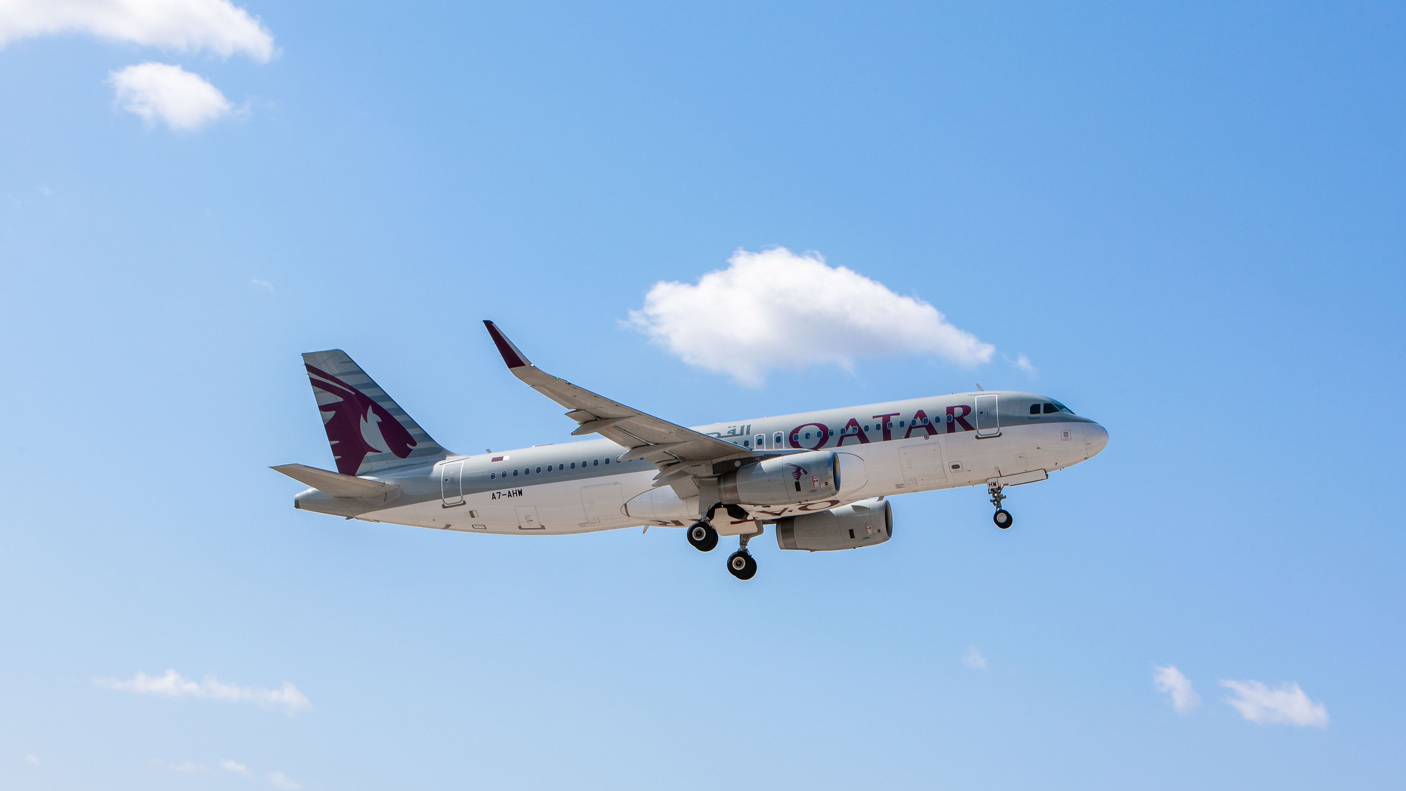 A Qatar Airways Airbus A320 flying in a blue sky