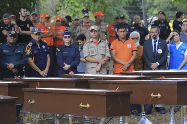 Police and firefighters attend the burial of nine unidentified migrants at the Sao Jorge cemetery, in Belem, Para state, Brazil, Thursday, April 25, 2024. The bodies of nine migrants found on an African boat off the northern coast of Brazil's Amazon region were buried Thursday with a solemn ceremony. (AP Photo/Paulo Santos)