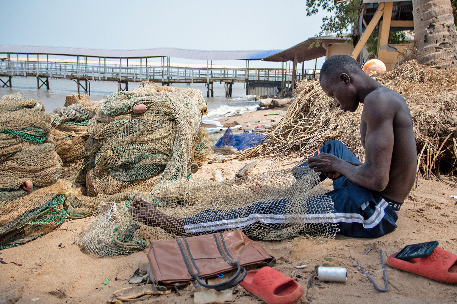 A fisherman repairs a beach seining net on Mahera Beach.