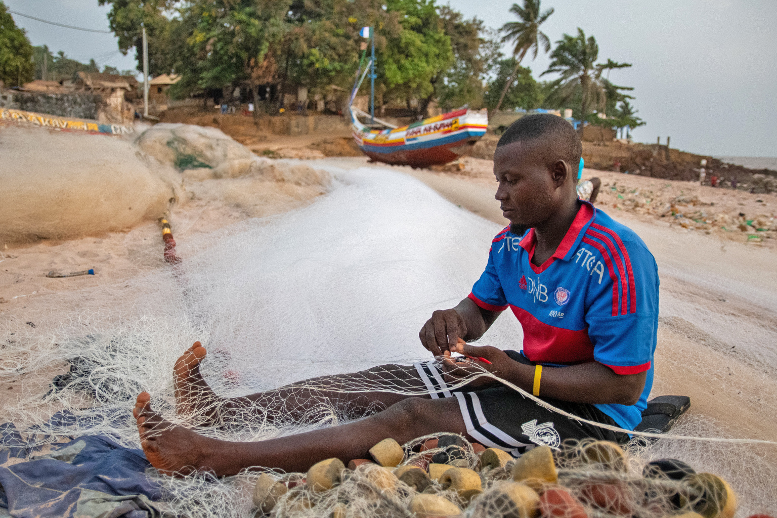 A fisherman repairs a net