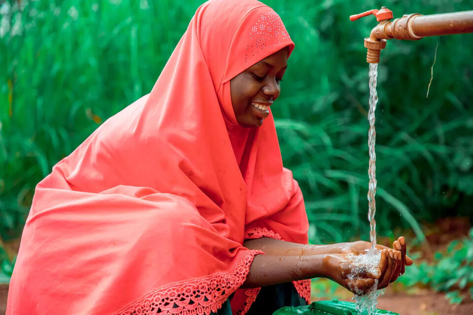 An adolescent girl fetches clean drinking water from an access point installed near her school in Kaguruka village, Kasulu district, Kigoma region, Tanzania, with support from UNICEF and partners.