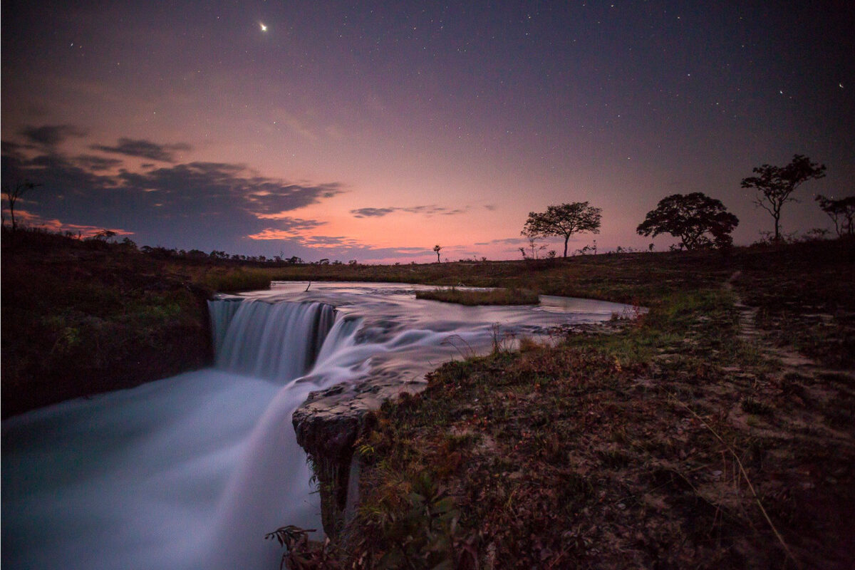 A waterfall glows in dusk light.