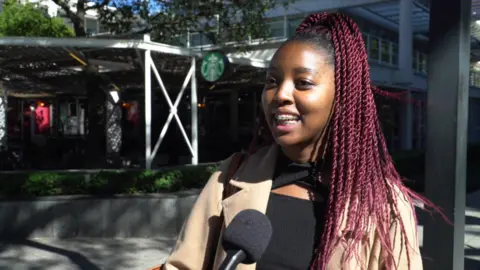 A woman with purple braids responds to a photographers questions.