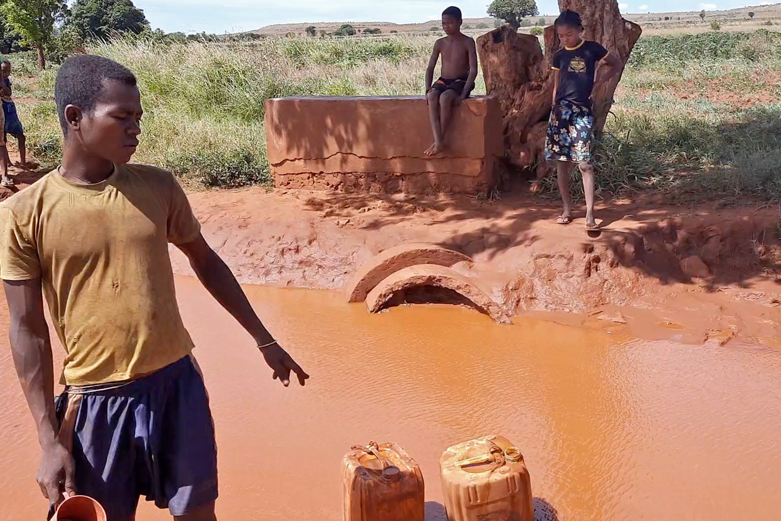 Komanga, 28, collecting water pooled on dirt road