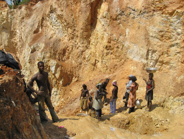 Several figures standing in a pit excavated in pale orange-brown earth. Image by Peter Lewenstein (CC BY-NC 2.0)