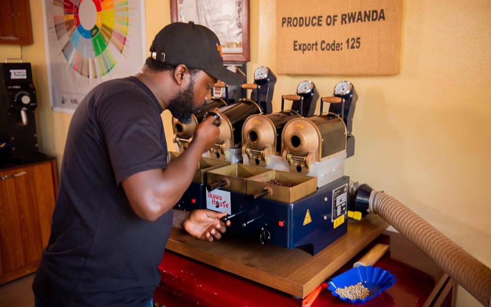 A Rwandan coffee professional uses a sample roaster.