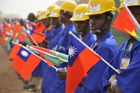 AFP Students at the vocational training center of reference (Centre de formation professionnelle de reference de Ziniare (CFPR-Z)) in Ziniare, 35kms of Ouagadougou hold Taiwan's and Burkina Faso's flags during the visit of Taiwan's President on April 9, 2012. Taiwan's President Ma Ying-jeou is on a three-leg trip to Burkina Faso, Gambia and Swaziland.