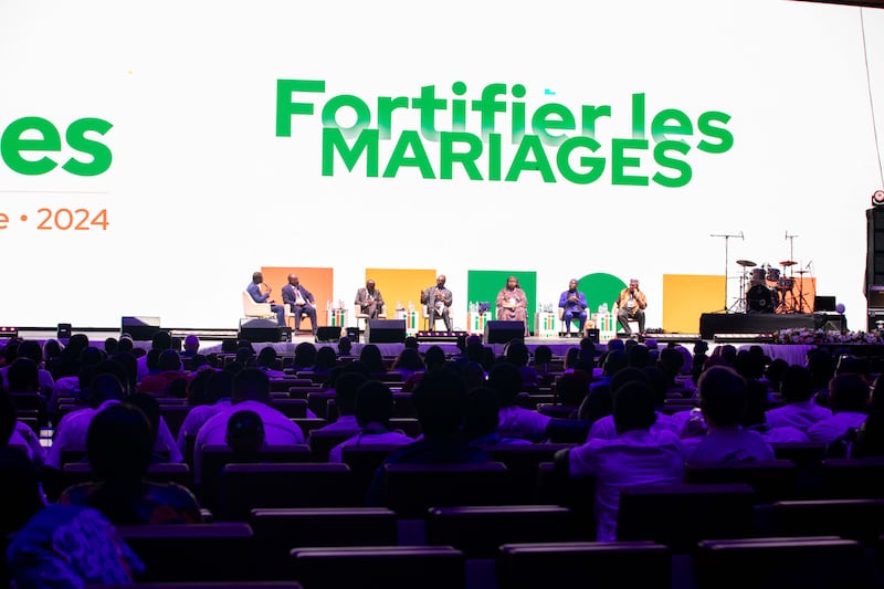 Panelists speak on stage during the 2024 Strengthening Families Conference in Abidjan, Ivory Coast. Behind them are the words 