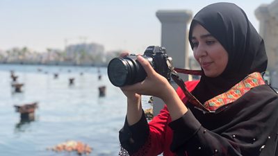 An El Kul journalist holds a camera preparing to take a photo.