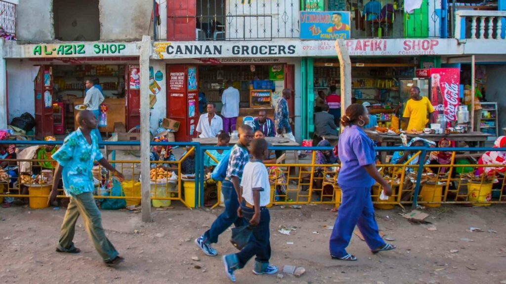 People walking in front of small colorful shops in Mombasa, Kenya