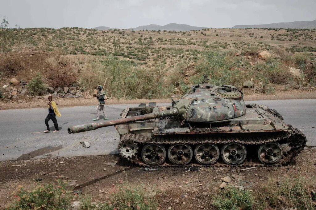 Farmers pass a tank that allegedly belonged to the Eritrean army on a road southwest of the Tigrayan capital, Mekele