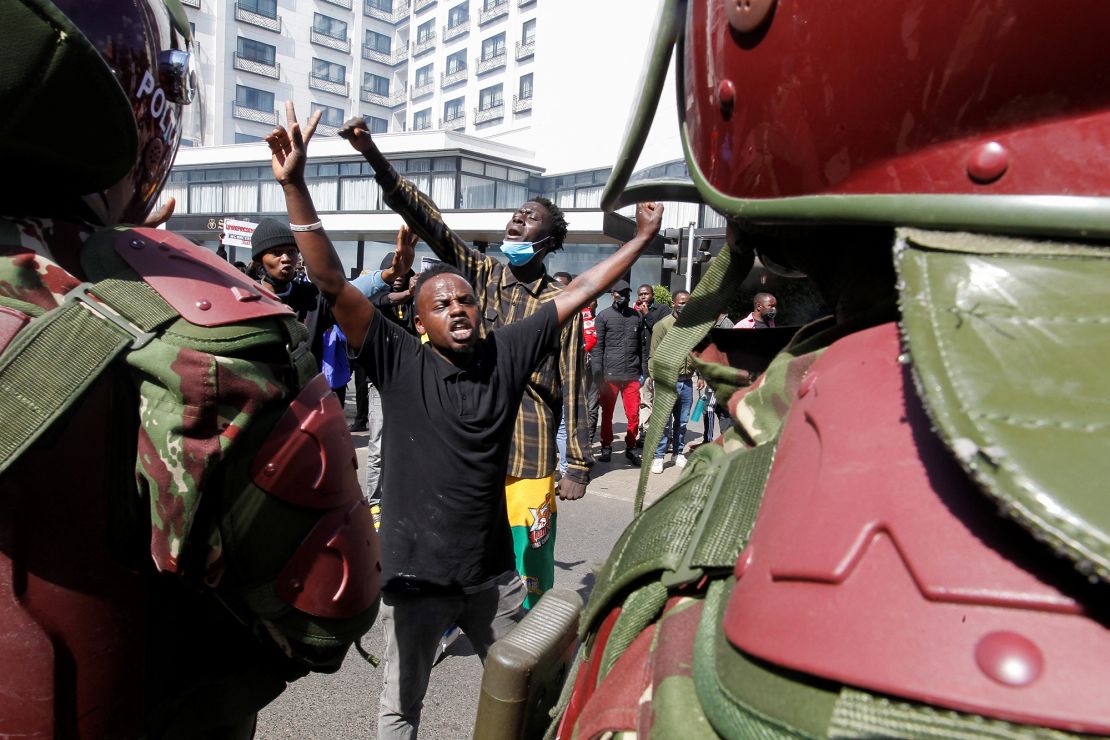 Demonstrators react as police stand guard