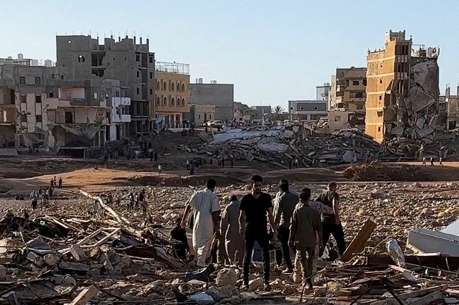 People walk through debris after a powerful storm and heavy rainfall hit Libya, in Derna, Libya, 12 September 2023