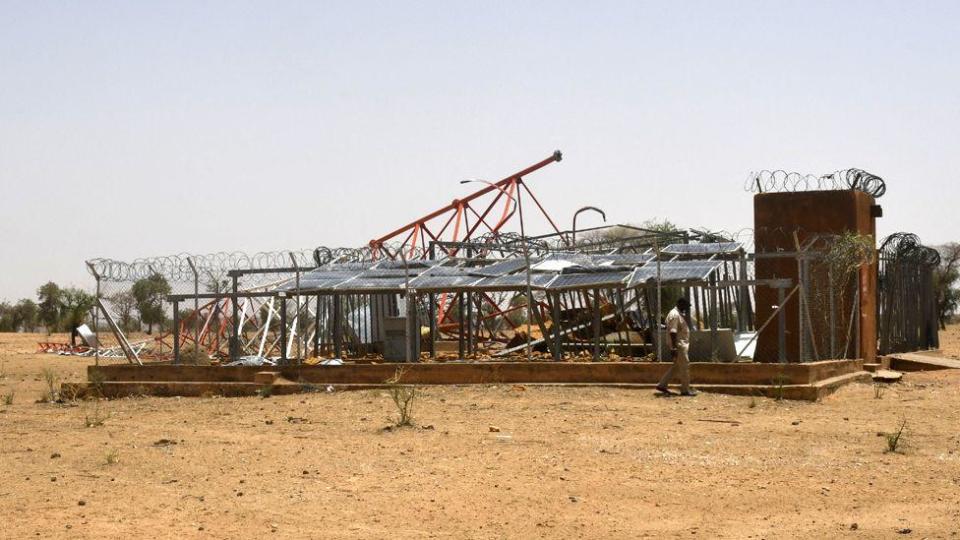 The remains of a telephone company’s antenna, surrounded by a few trees and bare ground 