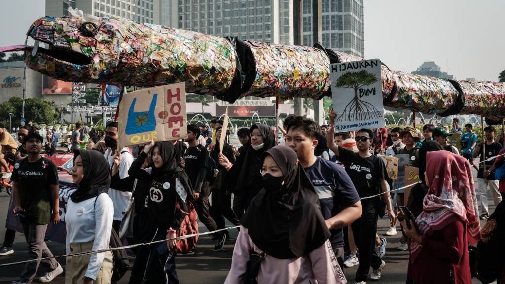 Youths hold placards and carry a snake-shaped obje