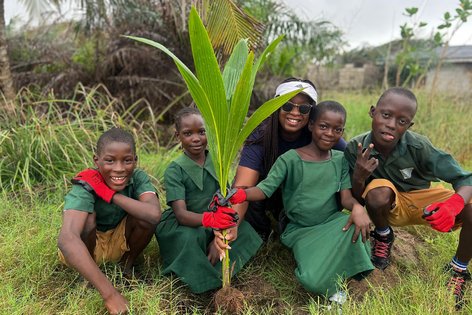 Doyinsola and school children pose while planting a sapling.