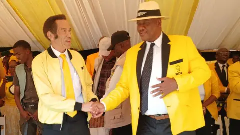 Innocent Selatlhwa Two men dressed in yellow shaking hands