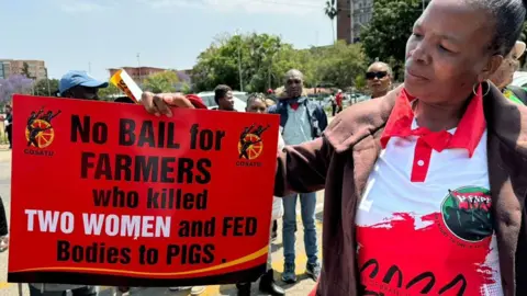 BBC A protester outside the court in Polokwane, holding a placard saying: